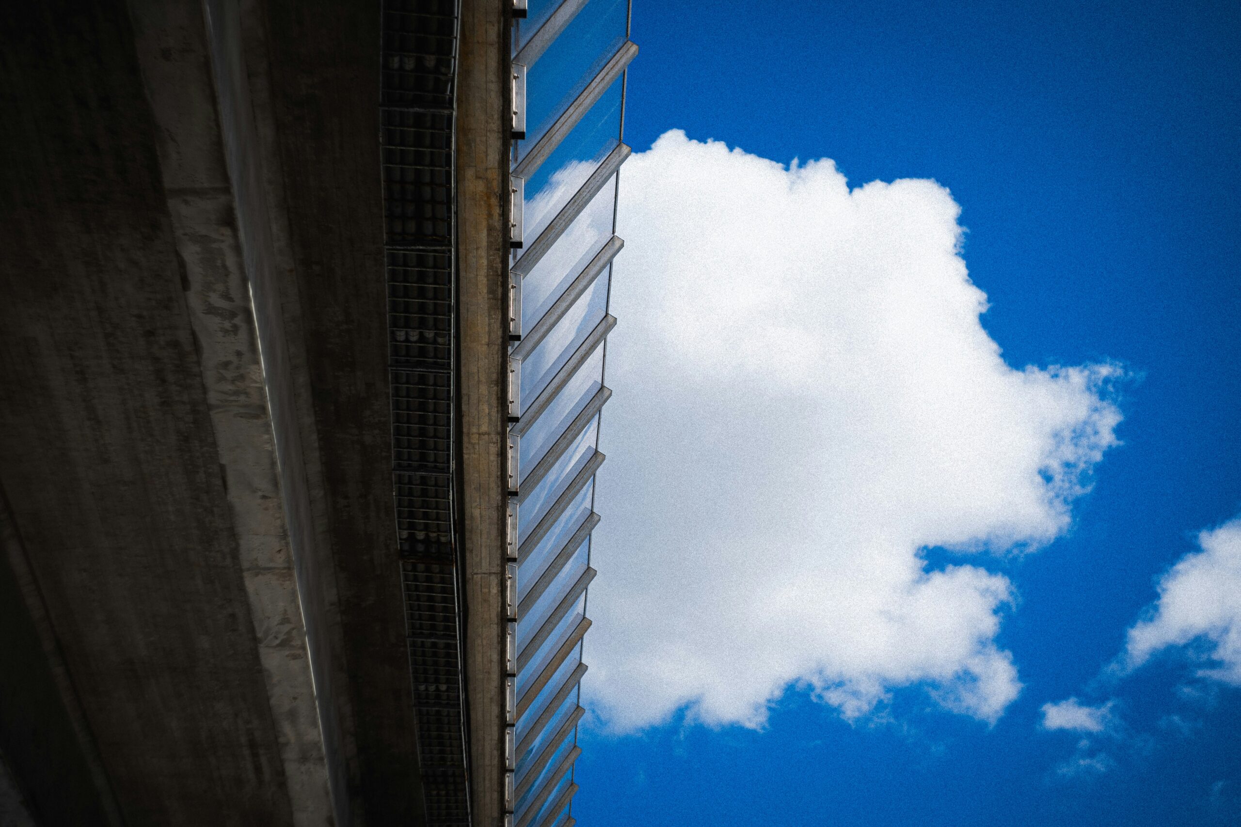 a cloud hiding behind a massive bridge.