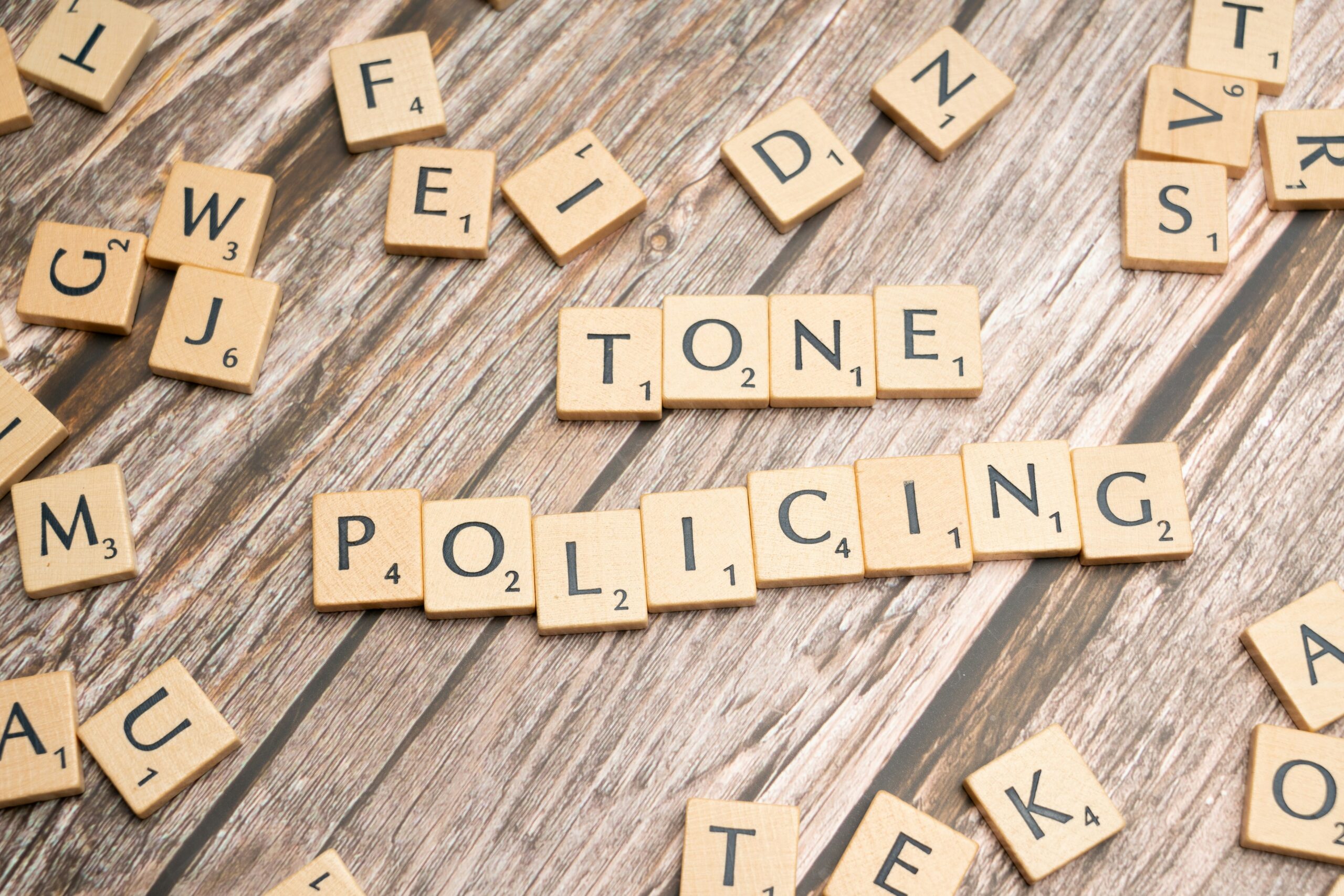 scrabble tiles spelling out the word tone police on a wooden table